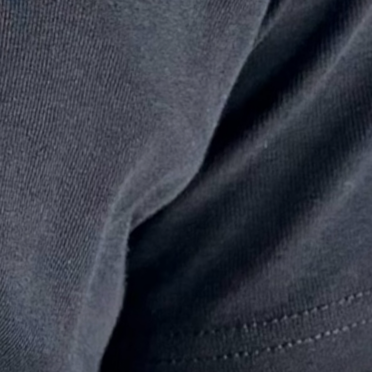 Close-up of dark charcoal gray fabric with visible knit texture and a stitched hem.